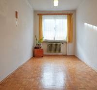 Szoba egy családi házban, fa dekoros padlóval, radiátorral és függönyös ablakkal.