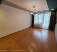 Nappali egy 4 szobás lakásban, fa mintázatú padlóval és nagy ablakkal.