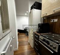 Konyha egy egyszobás lakásban fa dekor padlóval, tűzhellyel és hűtőszekrénnyel.