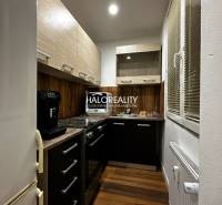 Konyha egy egyszobás lakásban fa dekor padlóval és sötét szekrényekkel.