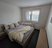 Hálószoba egy kétszobás lakásban ággyal, éjjeliszekrényekkel és faldekorációval.