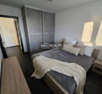 Hálószoba egy kétszobás lakásban sötét padlóval, nagy szekrénnyel és egyszerű bútorokkal.