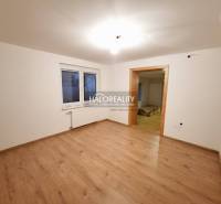 Egy családi ház szobája fa mintázatú padlóval és fehér falakkal.