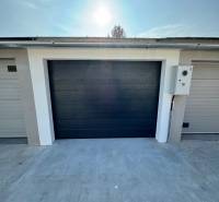 Garázsok a Nap utcában Komáromban sötét kapukkal és betonfelülettel.