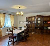 Tágas étkező egy családi házban nagy asztallal és fa nappali szekrénnyel.