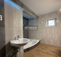 Családi ház fürdőszobája káddal, mosdóval és fa dekoros padlóval.