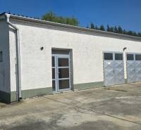 Fehér épület fém ajtókkal a város raktár- és csarnokövezetében, Vágsellyén.