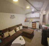 Nappali a házban kényelmes kanapéval, konyhapulttal és dekoratív falburkolattal.