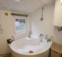 A ház fürdőszobája kádat, bojleret és egy kis ablakot mutat, amely kilátást nyújt.