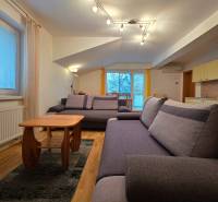 Világos nappali a nyaraló apartmanban kényelmes kanapékkal és fa hatású padlóval.