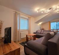 Nappali a nyaraló apartmanban kényelmes kanapékkal és fa dekorációjú padlóval.