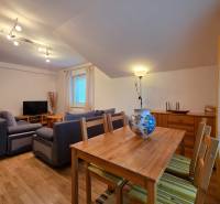 Nappali a nyaraló apartmanban fa dekor padlóval, kanapéval és étkezőasztallal.