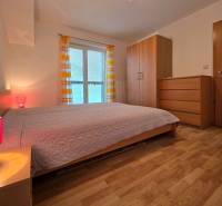 Hálószoba egy üdülő apartmanban fa dekor padlóval, ággyal és szekrénnyel.