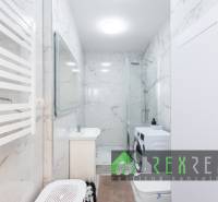 Fürdőszoba zuhanyzóval, mosógéppel és márványfallal egy háromszobás lakásban.