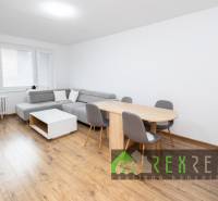 Nappali sarokkanapéval, étkezőasztallal és fa mintázatú padlóval.