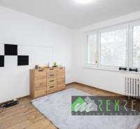 Szoba egy háromszobás lakásban, fa dekorációjú padlóval és nagy ablakkal.