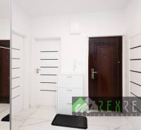 Folyosó fehér ajtókkal és tükrös szekrénnyel egy háromszobás lakásban.