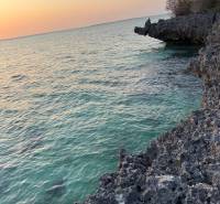 Tengerparti sziklák és naplemente a tenger enyhe hullámai felett Kizimkaziban, Földterületek - kereskedelmi célú.