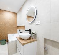 Két szobás lakás fürdőszobája világos csempékkel és fa dekorációjú padlóval.