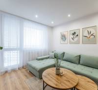 Nappali egy kétszobás lakásban kanapéval, képekkel és fa dekor padlóval.