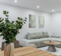 A 3 szobás lakás nappalija kanapéval, asztallal és virágokkal világos árnyalatokban.