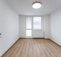 Szoba egy háromszobás lakásban fa dekor padlóval és nagy ablakkal.