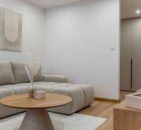 Nappali egy háromszobás lakásban kanapéval és dohányzóasztallal, fa dekorációjú padlóval.