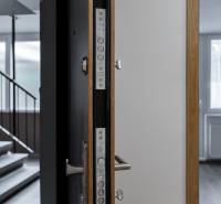 Nyitott ajtó egy háromszobás lakásba, látható a fa mintázatú padló és az ablak.