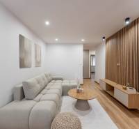 Nappali egy háromszobás lakásban kanapéval és fa dekorációjú padlóval.