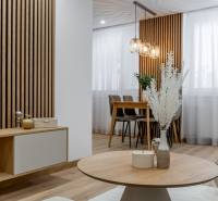 Nappali kialakítása egy háromszobás lakásban fa dekor padlóval és stílusos lámpatestekkel.