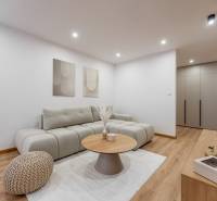 Nappali egy háromszobás lakásban kényelmes kanapéval és fa mintázatú padlóval.