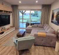 Nappali egy családi házban fa dekoros padlóval, sarokkanapéval és televízióval.