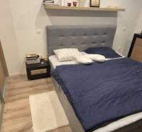 Hálószoba fa dekorációjú padlóval, ággyal és tárolóhelyekkel egy családi házban.