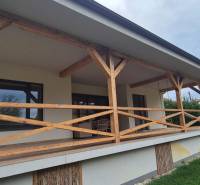 A Studienka-i családi háznak van egy terasza fa korláttal és mellette gyep.