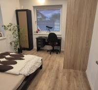 Hálószoba ággyal, asztallal és fa dekorációjú padlóval egy családi házban.