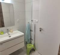 Fürdőszoba családi házban mosdóval, dombornyomott csempékkel, tükörrel és megvilágított falakkal.