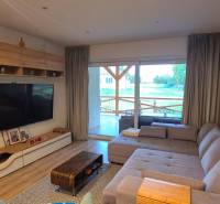 Családi ház nappalija kanapéval, nagy televízióval és fa dekorációjú padlóval.