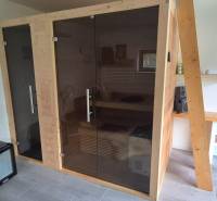 Családi ház belső tere szaunával, ventilátorral és faasztalon lévő mosdókagylóval.