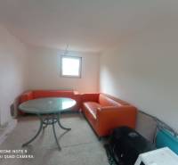 Narancssárga kanapék és kerek asztal egészítik ki a fehér falú ház belső terét.