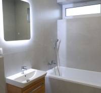 Fürdőszoba káddal és mosdóval, kiegészítve megvilágított tükörrel egy családi házban.