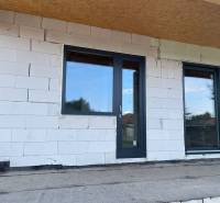 Befejezetlen családi ház homlokzata Radaván műanyag ajtókkal és ablakokkal.