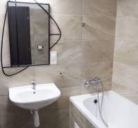 Fürdőszoba káddal, mosdóval és tükörrel, homokszínű csempékkel.