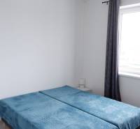 Hálószoba családi házban kék ágytakarókkal és rolókkal.