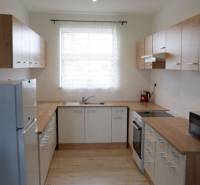 Konyha családi házban fehér szekrényekkel és fa dekoros padlóval.