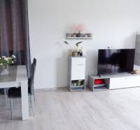 Családi ház belső tere étkezőasztallal, televízióval és fa dekorációjú padlóval.