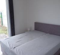 Hálószoba családi házban ággyal és padlóig érő nagy ablakokkal, fa dekorációval.