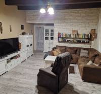 Nappali sarokkanapéval, fehér bútorokkal és fa dekorációjú padlóval egy családi házban.