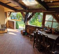 Családi ház rusztikus terasza fa bútorokkal és kilátással a kertre.