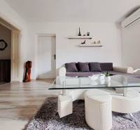 Nappali egy családi házban kanapéval, üvegasztallal és fa dekorációjú padlóval.