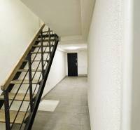 Családi ház folyosója minimalista lépcsőkkel, világos falakkal és csempével.